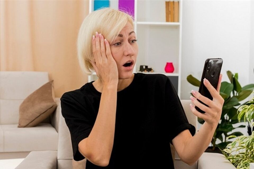 Frau erschrocken mit smartphone in der Hand